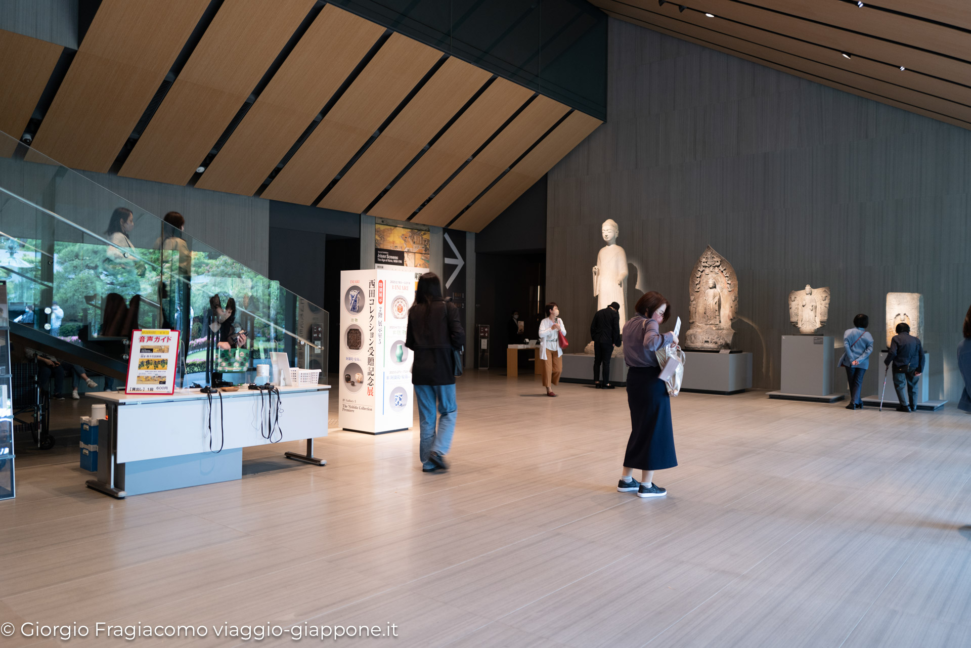 Interno di un museo in Giappone, visitatori ammirano statue e opere d'arte tradizionale.