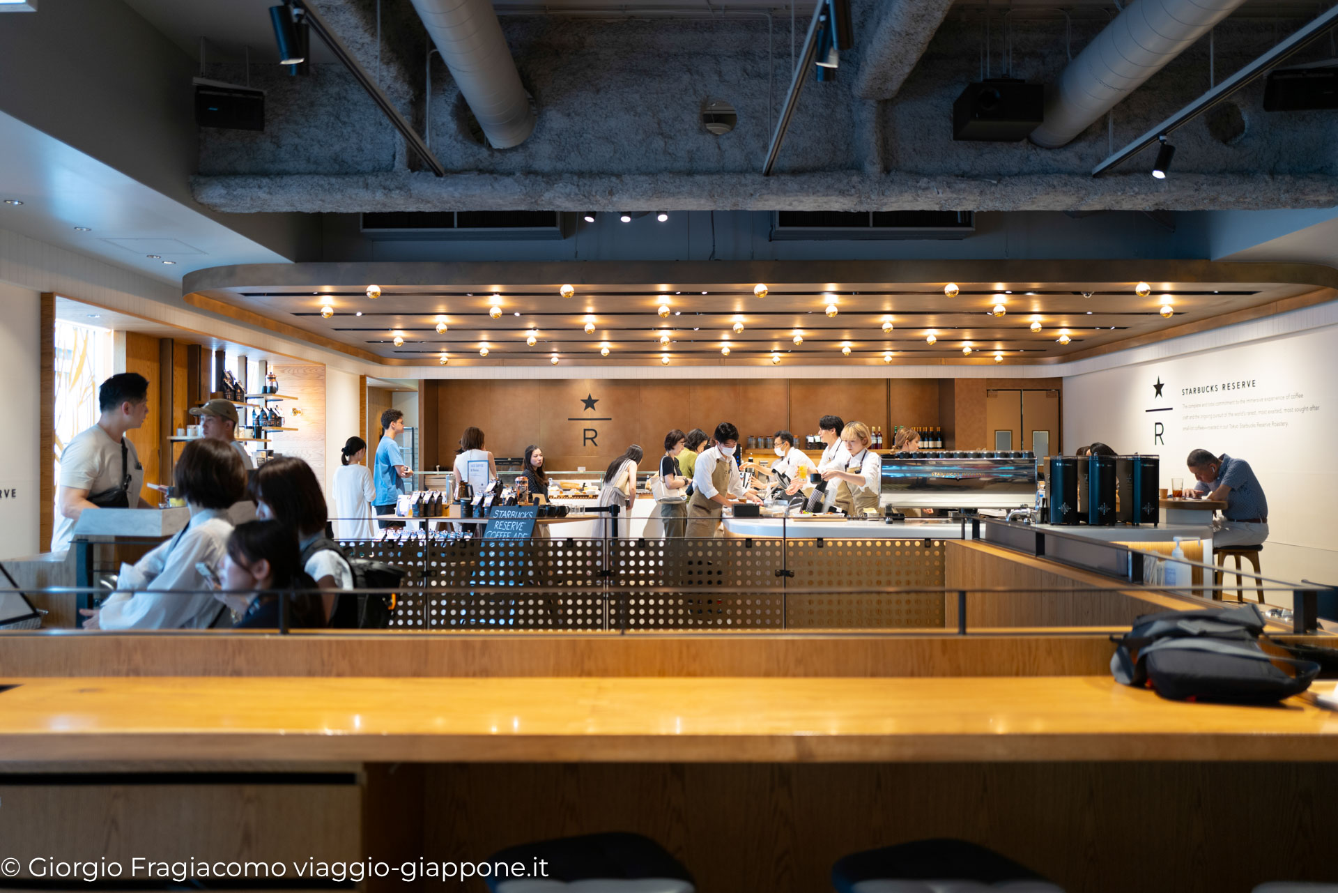 Interno di un caffè Starbucks Reserve in Giappone, con clienti e baristi al lavoro in un ambiente moderno.